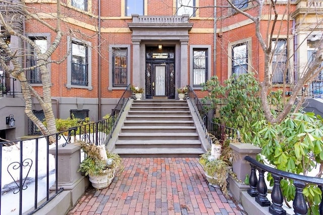 view of exterior entry with brick siding and fence