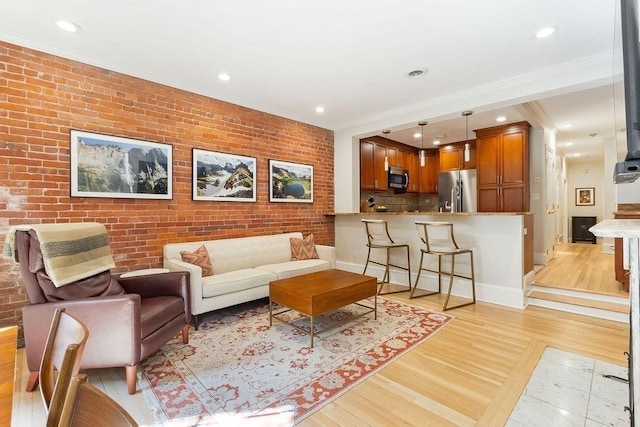 living room featuring recessed lighting, brick wall, baseboards, light wood-style floors, and crown molding