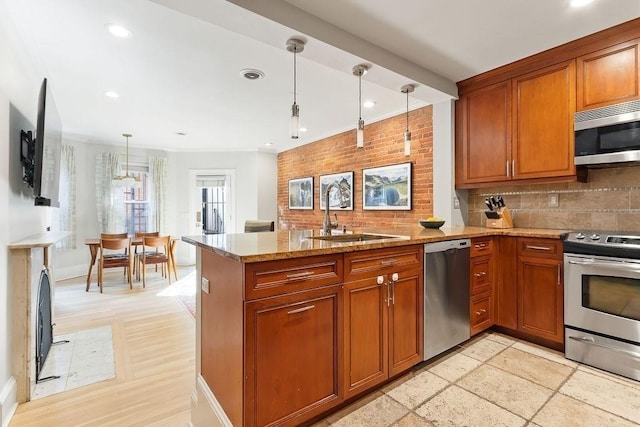 kitchen with light stone counters, brown cabinets, a peninsula, stainless steel appliances, and a sink