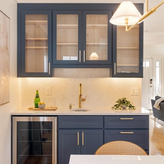 bar featuring sink, blue cabinets, beverage cooler, and tasteful backsplash