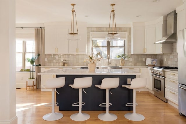 kitchen featuring white cabinetry, wall chimney range hood, high end stove, and a kitchen island