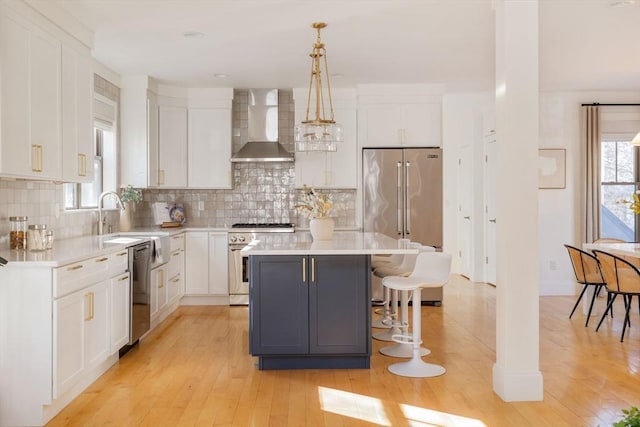 kitchen with white cabinets, a center island, wall chimney exhaust hood, and high end appliances