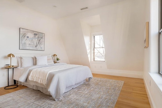 bedroom with multiple windows and light hardwood / wood-style flooring