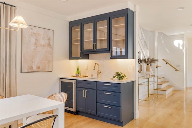 bar featuring pendant lighting, wine cooler, sink, light wood-type flooring, and blue cabinets