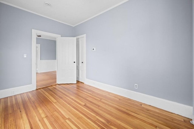 spare room with light wood-style flooring, crown molding, and baseboards