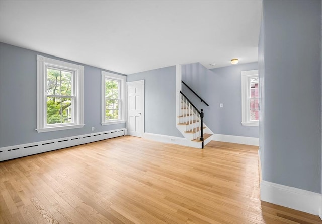 unfurnished living room featuring a baseboard radiator, stairs, light wood-style flooring, and baseboards
