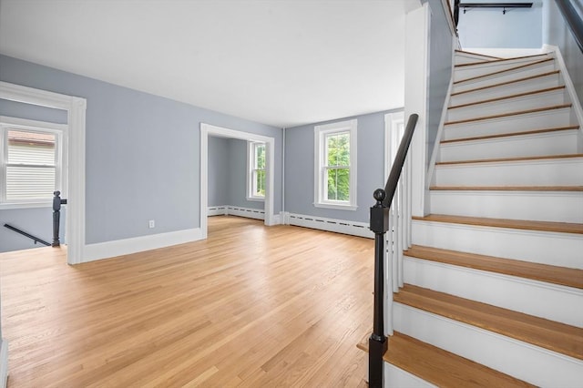 staircase featuring a baseboard heating unit, wood finished floors, and baseboards