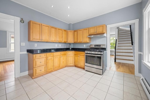 kitchen featuring stainless steel gas range, a baseboard heating unit, under cabinet range hood, dark countertops, and ornamental molding