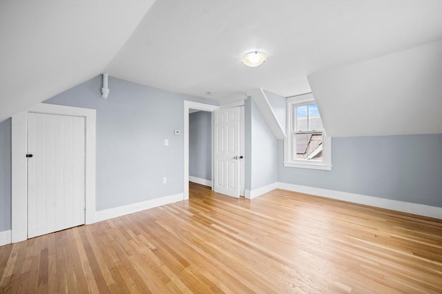 bonus room with light wood-type flooring, vaulted ceiling, and baseboards