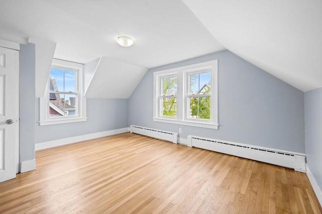 bonus room with a baseboard radiator, wood finished floors, lofted ceiling, and baseboards