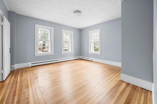 unfurnished room featuring baseboard heating, baseboards, and light wood-style floors
