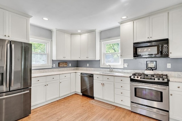 kitchen featuring a sink, stainless steel appliances, a wealth of natural light, and white cabinetry