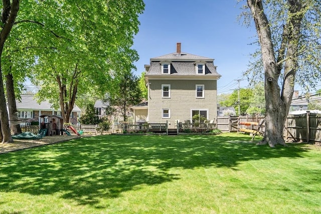 rear view of house with a chimney, a fenced backyard, a lawn, roof with shingles, and a playground