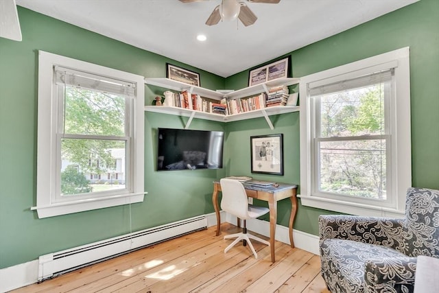 office featuring a baseboard heating unit, a healthy amount of sunlight, a ceiling fan, and hardwood / wood-style flooring