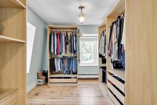 spacious closet with a baseboard radiator and light wood-style floors