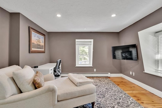 living area with a baseboard heating unit, baseboards, recessed lighting, and wood finished floors