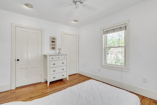 bedroom with light wood-type flooring, baseboards, and ceiling fan