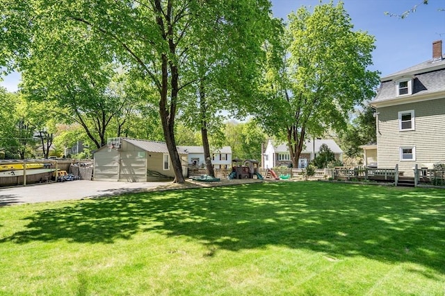 view of yard featuring a playground, an outdoor structure, and fence