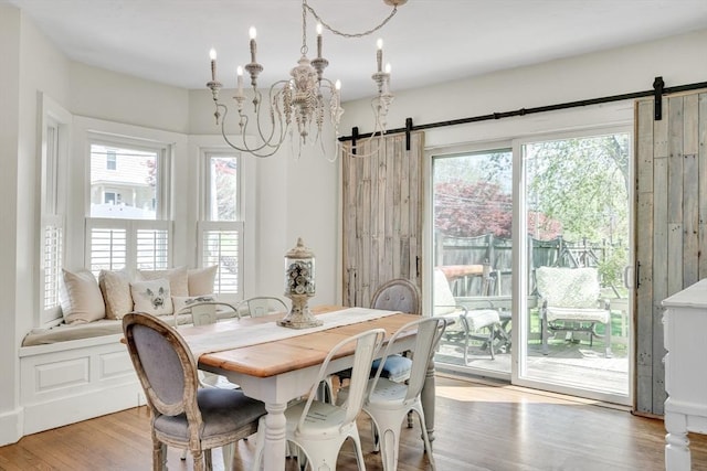 dining space with wood finished floors, a barn door, and a healthy amount of sunlight