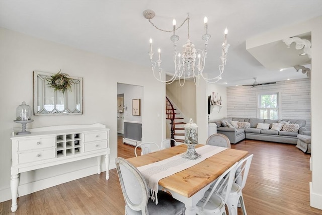 dining area with a chandelier, stairs, a baseboard radiator, and wood finished floors