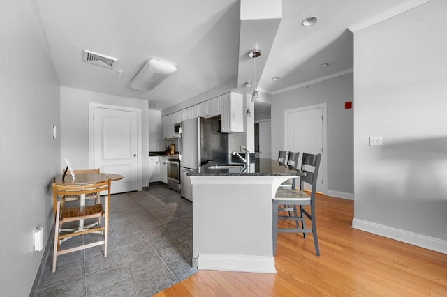 kitchen with stainless steel appliances, a breakfast bar, sink, white cabinetry, and kitchen peninsula