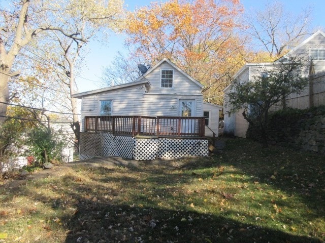 rear view of house featuring a lawn and a deck