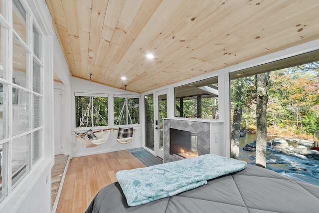 sunroom / solarium featuring a tiled fireplace, plenty of natural light, wooden ceiling, and lofted ceiling