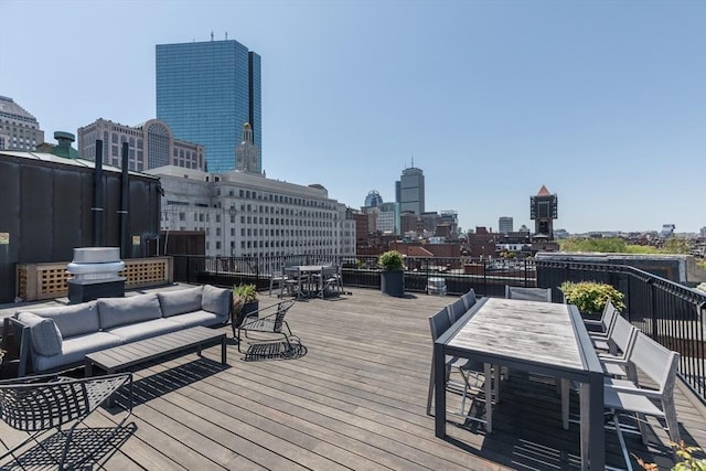 deck featuring outdoor dining area, a view of skyline, and an outdoor hangout area