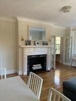 living room with a fireplace, baseboards, crown molding, and wood finished floors