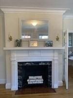 detailed view of a fireplace with flush hearth, ornamental molding, and wood finished floors