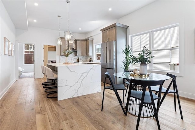 157 Princeton St Unit 1, Boston, MA 02128 - kitchen with stainless steel refrigerator, a breakfast bar, light wood-type flooring, backsplash, and a kitchen island