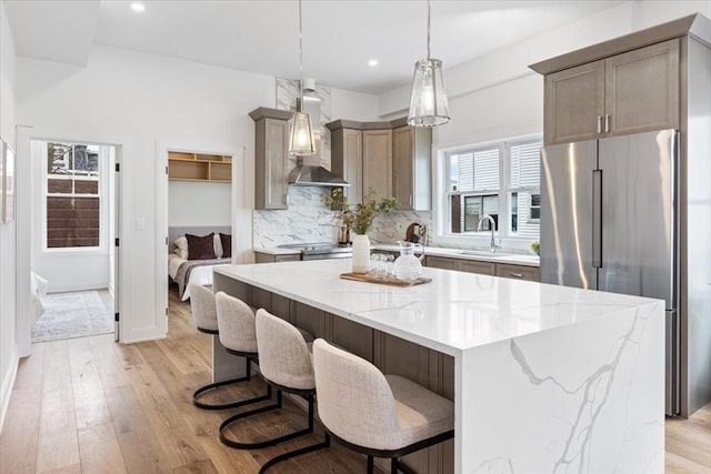 157 Princeton St Unit 1, Boston, MA 02128 - kitchen featuring wall chimney range hood, stainless steel fridge, tasteful backsplash, light wood finished floors, and a kitchen island