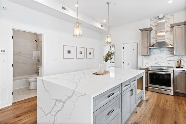 157 Princeton St Unit 1, Boston, MA 02128 - kitchen featuring stainless steel electric range oven, wall chimney range hood, gray cabinetry, decorative light fixtures, and light stone counters