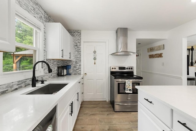 186 Andover St, North Andover, MA 01845 - kitchen with electric stove, wall chimney range hood, light wood-style flooring, decorative backsplash, and light countertops