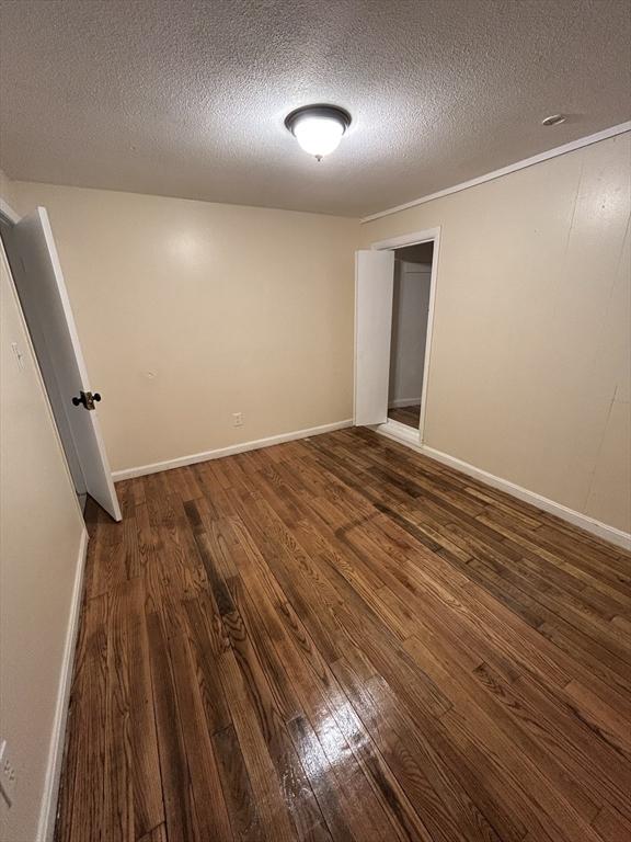 spare room featuring dark wood-type flooring and a textured ceiling