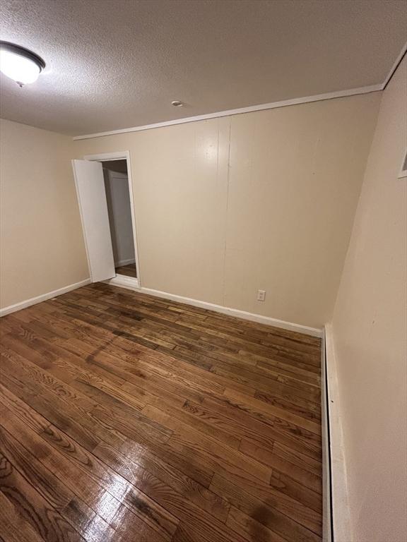 empty room featuring a textured ceiling and dark wood-type flooring