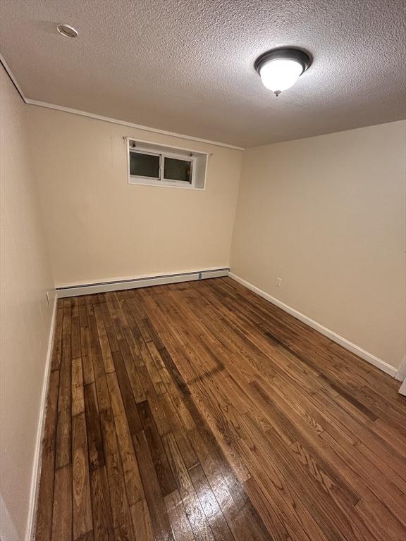 unfurnished room with hardwood / wood-style flooring, a textured ceiling, and a baseboard radiator