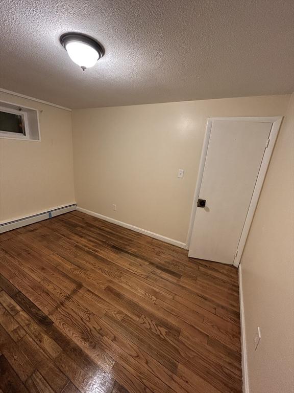 empty room with a textured ceiling and dark wood-type flooring