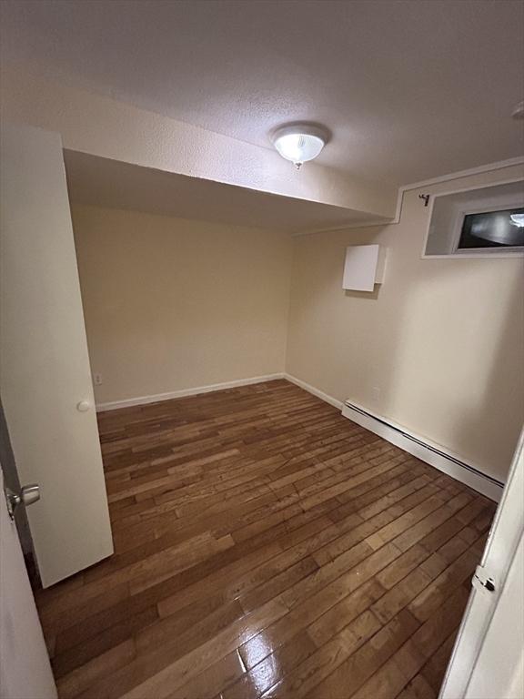 basement featuring dark hardwood / wood-style flooring and a baseboard radiator