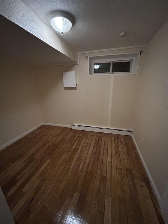 interior space featuring dark hardwood / wood-style flooring, a textured ceiling, and a baseboard heating unit