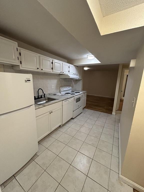 kitchen with tasteful backsplash, white appliances, sink, light tile patterned floors, and white cabinets