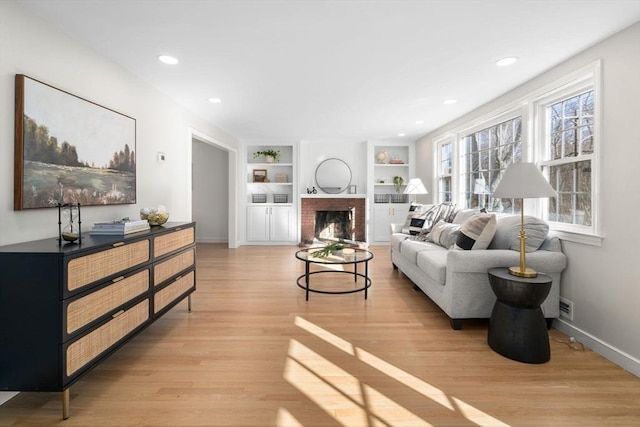110 Westover Pkwy, Norwood, MA 02062 - living area with built in shelves, light wood finished floors, baseboards, a brick fireplace, and recessed lighting