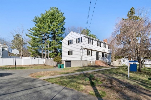 110 Westover Pkwy, Norwood, MA 02062 - view of front of house with a chimney, a front lawn, fence, and aphalt driveway