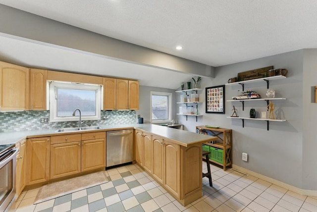 kitchen featuring light brown cabinets, decorative backsplash, a sink, and stainless steel appliances