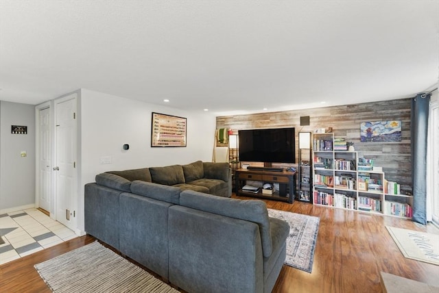living room with recessed lighting, an accent wall, baseboards, and wood finished floors