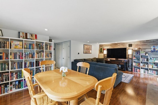 dining room with wooden walls, recessed lighting, and wood finished floors
