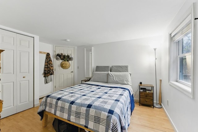 bedroom featuring light wood-style flooring, a closet, and baseboards