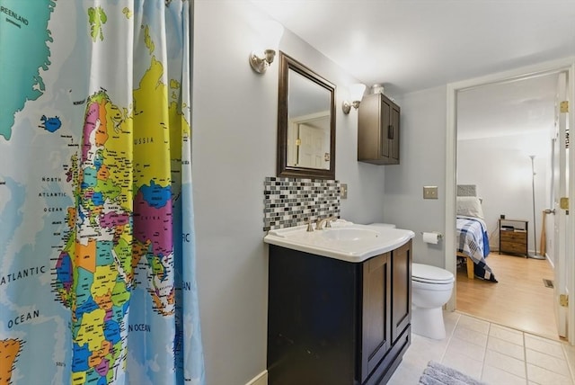 ensuite bathroom featuring toilet, connected bathroom, vanity, backsplash, and tile patterned floors