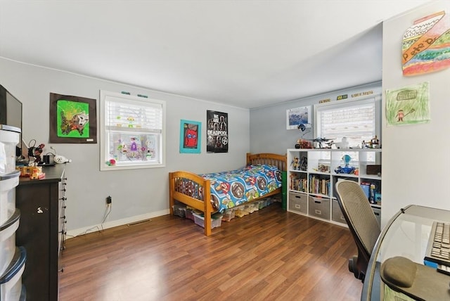 bedroom featuring multiple windows, baseboards, and wood finished floors