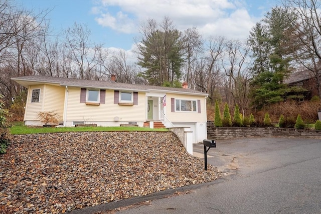 single story home featuring driveway, a chimney, and an attached garage